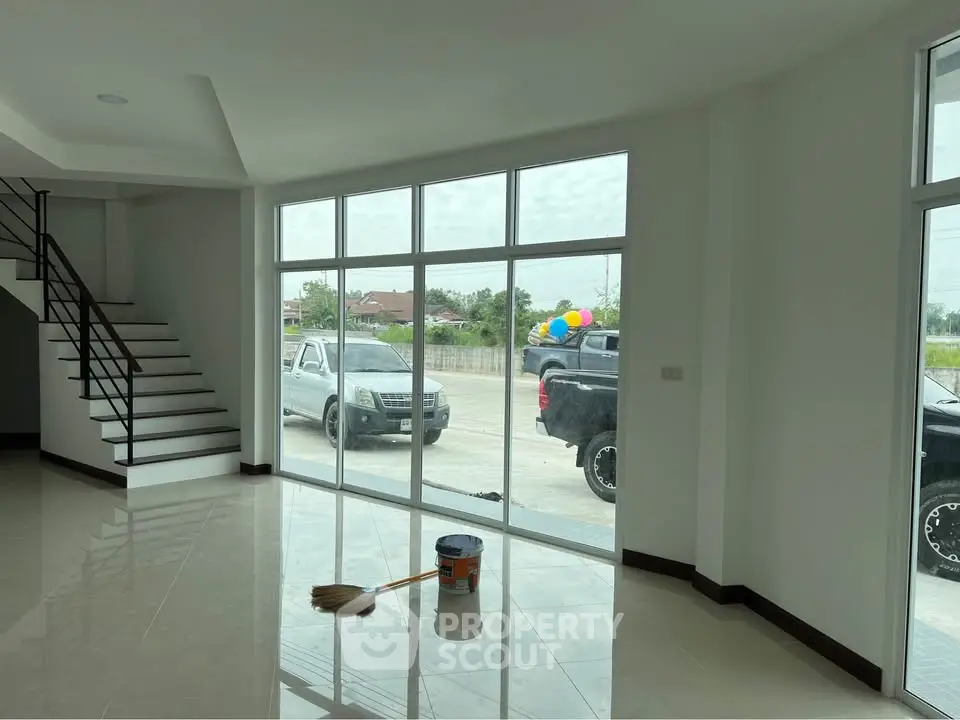 Spacious modern living room with large windows and staircase, perfect for natural light lovers.