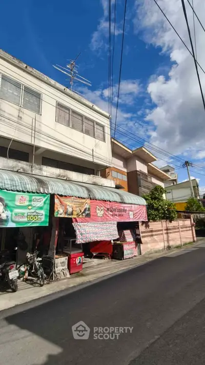 Charming street view of mixed-use building with shops and residential units under a clear blue sky.
