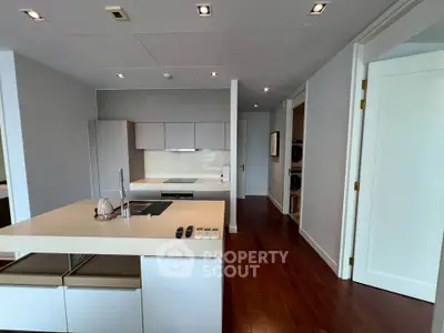 Modern kitchen with sleek design and open layout, featuring an island and hardwood floors.