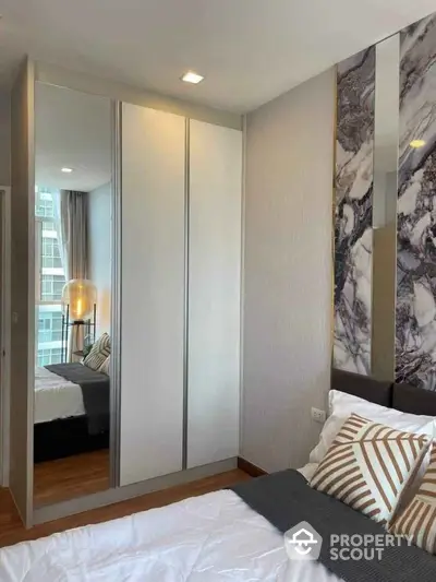 Modern bedroom with stylish decor and mirrored wardrobe in urban apartment.