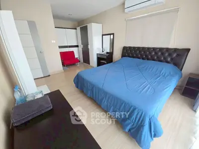 Spacious bedroom with modern decor and blue bedding in a stylish apartment.