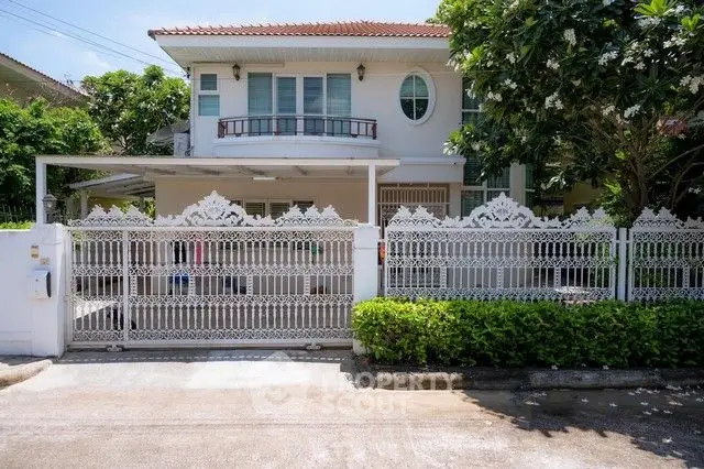 Charming two-story house with ornate white fence and lush greenery