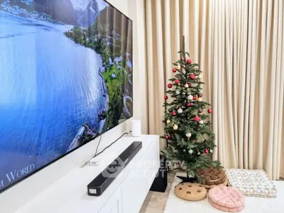 Cozy living room with Christmas tree and large TV, perfect for holiday gatherings.