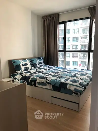 Modern bedroom with large window and stylish bedding in urban apartment