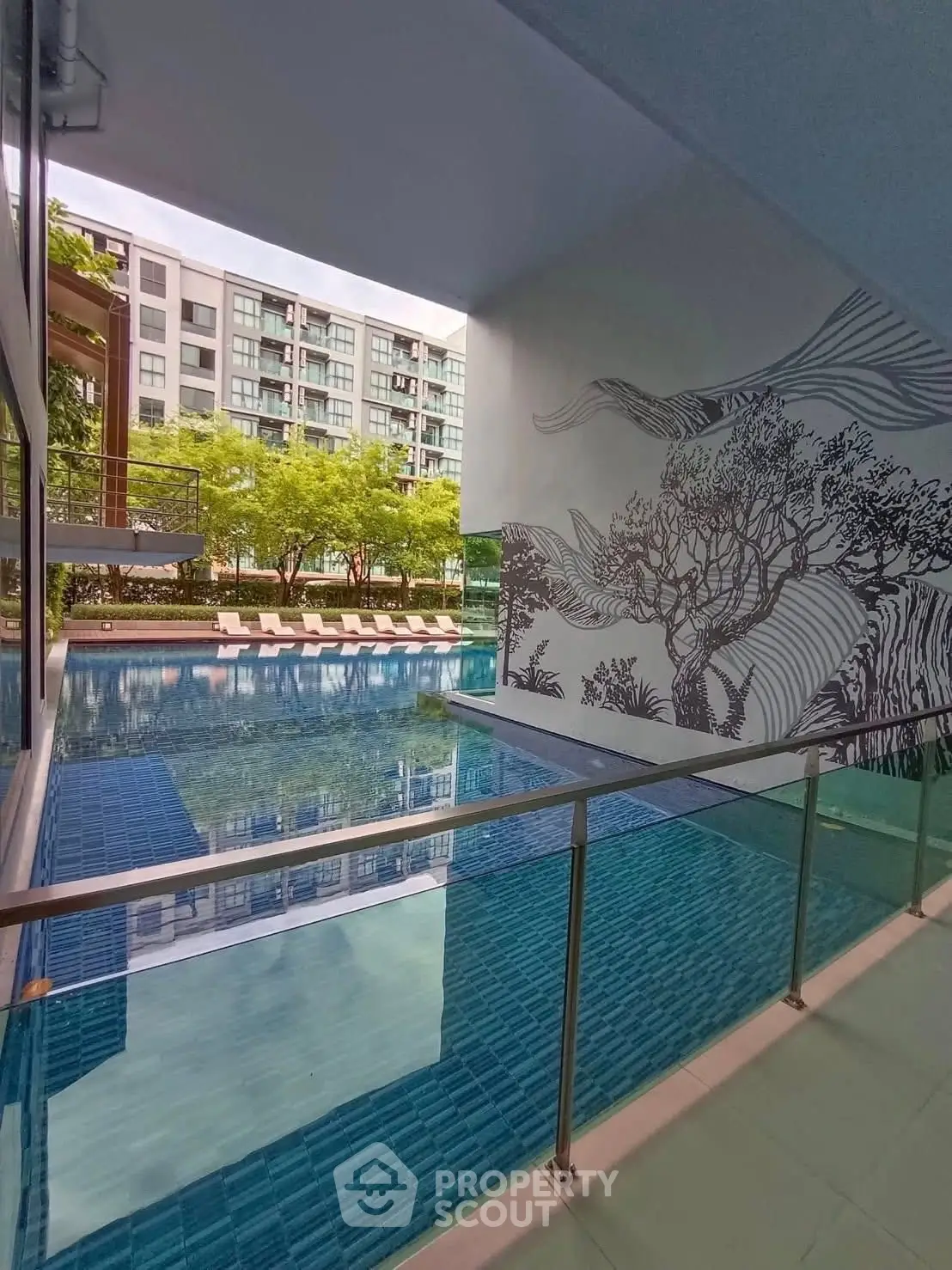 Luxurious condominium pool area with modern design and lush greenery view.