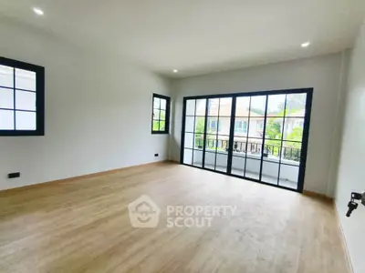 Spacious empty room with large windows and wooden flooring, perfect for customization.