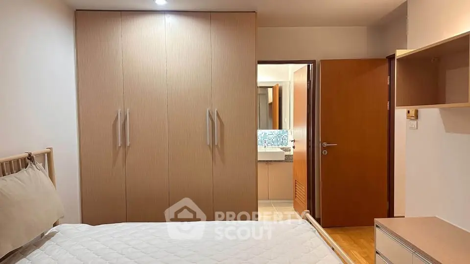 Cozy bedroom with modern wardrobe and ensuite bathroom in a stylish apartment.