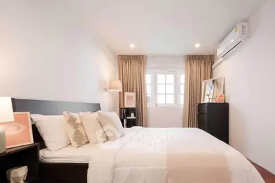 Cozy bedroom with elegant decor, featuring a comfortable bed, stylish lighting, and air conditioning.