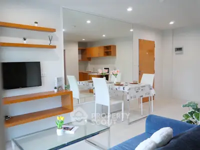 Modern living room with open kitchen, stylish shelving, and cozy dining area in a contemporary apartment.
