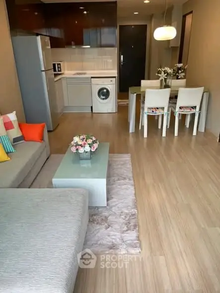 Modern open-plan living room with kitchen, featuring sleek furniture and appliances, ideal for urban living.