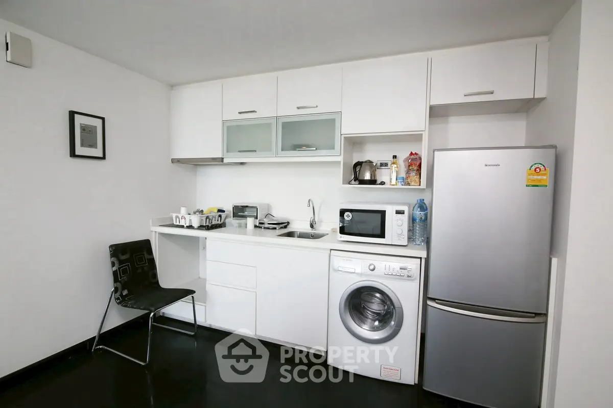 Modern compact kitchen with appliances including washing machine and fridge in sleek white design.