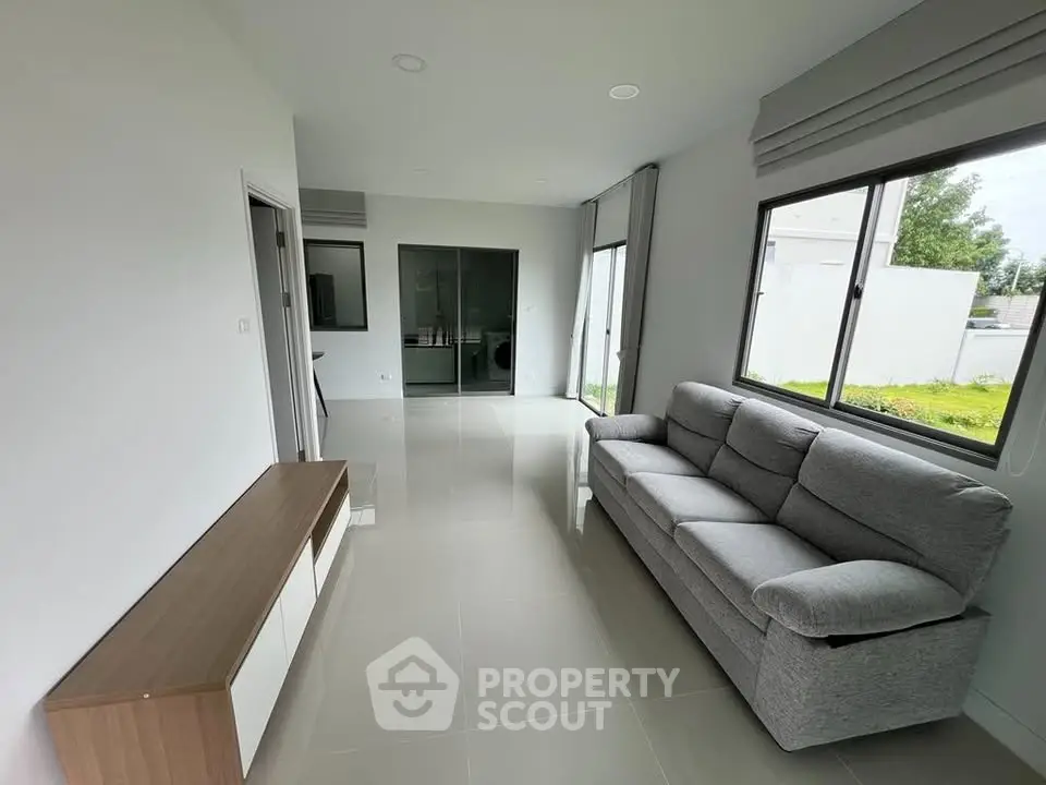 Modern living room with sleek furniture and large windows offering natural light.