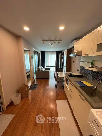 Modern open-plan kitchen and living area with wooden flooring and natural light.
