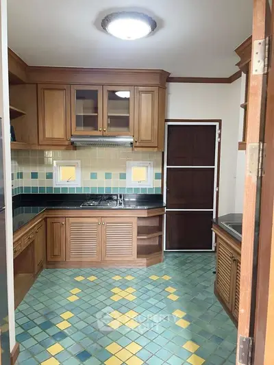 Charming kitchen with wooden cabinets and colorful tiled floor, featuring a gas stove and ample storage space.