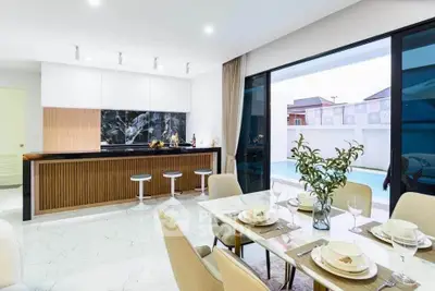 Luxurious modern kitchen and dining area with pool view, featuring sleek design and elegant decor.