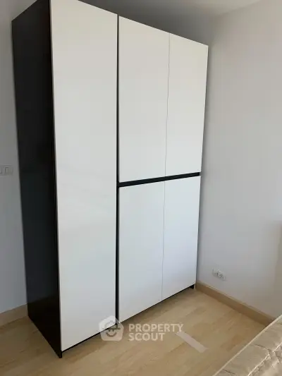 Modern white wardrobe in a minimalist bedroom with light wood flooring.