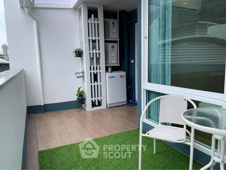 Charming balcony with artificial grass and cozy seating, perfect for relaxation and enjoying city views.
