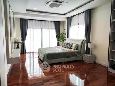 Spacious bedroom with elegant decor and large windows for natural light.