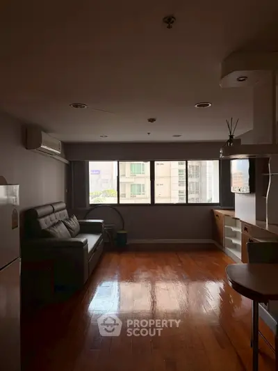 Spacious living room with wooden flooring and large windows offering city views.