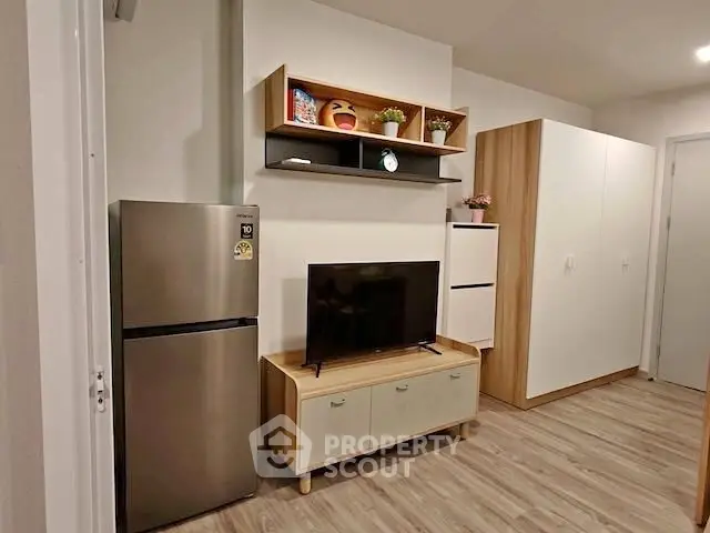 Modern living room with sleek fridge and stylish TV stand in cozy apartment.