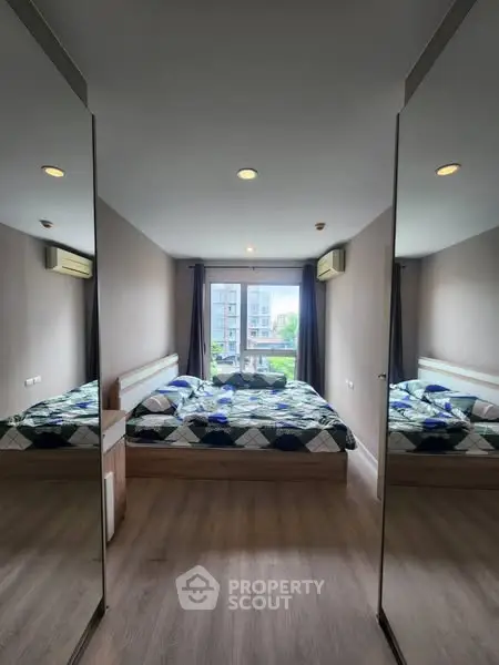Spacious bedroom with mirrored closets and large window view