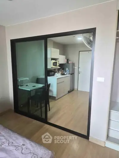 Modern apartment with open kitchen and sliding glass doors, featuring sleek cabinetry and dining area.