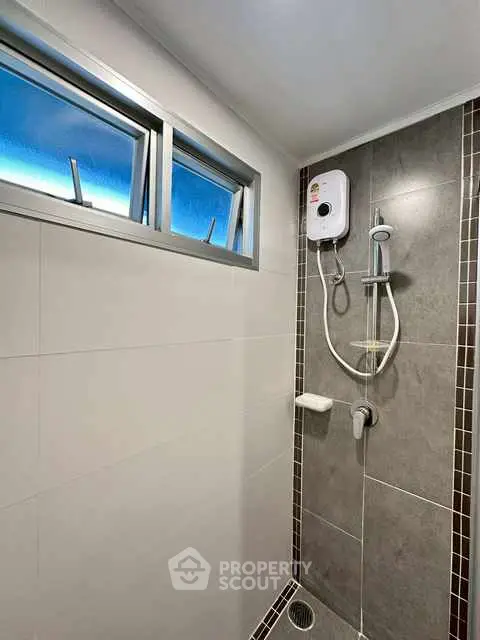 Modern bathroom shower with sleek design and natural light window.