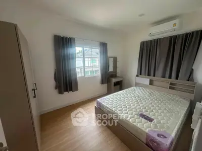 Spacious bedroom with large window and modern furnishings in a bright, airy home.