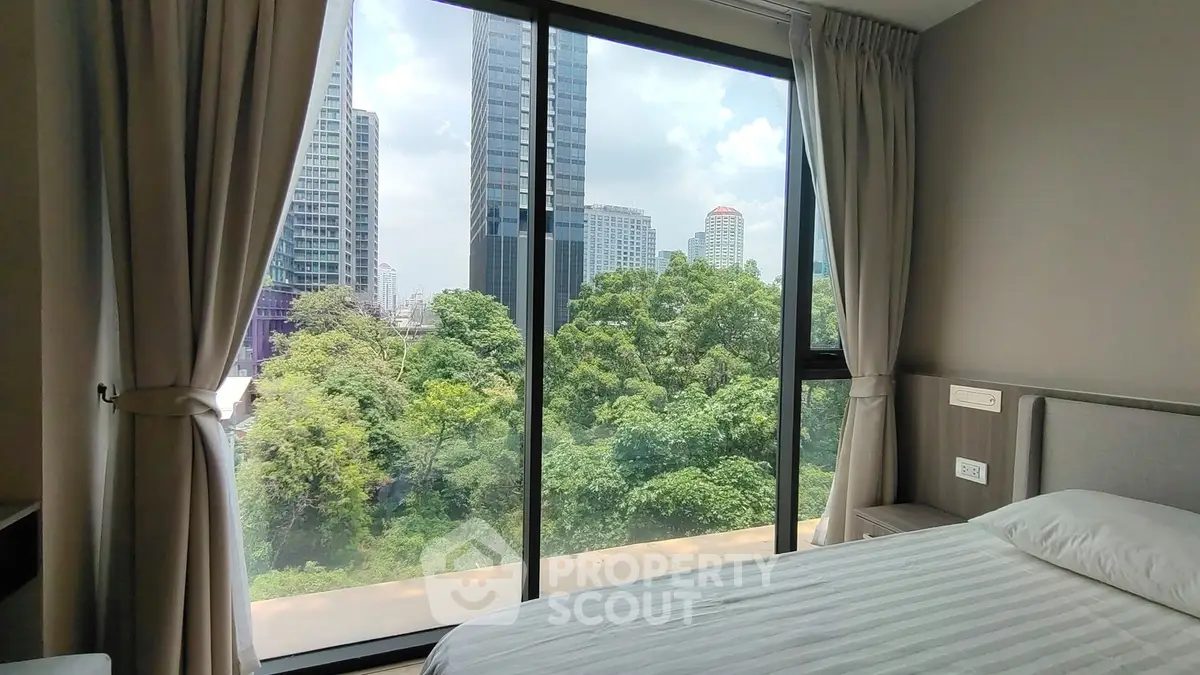 Spacious bedroom with floor-to-ceiling windows offering stunning city and greenery views.