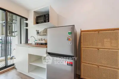 Modern kitchen with sleek fridge and microwave, open shelving, and balcony view.