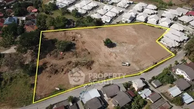 Aerial view of a large plot of land outlined in yellow, surrounded by residential houses.