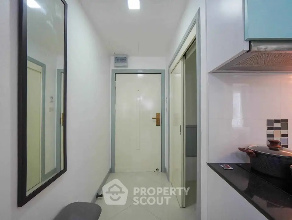 Modern apartment hallway with sleek kitchen entrance and large mirror