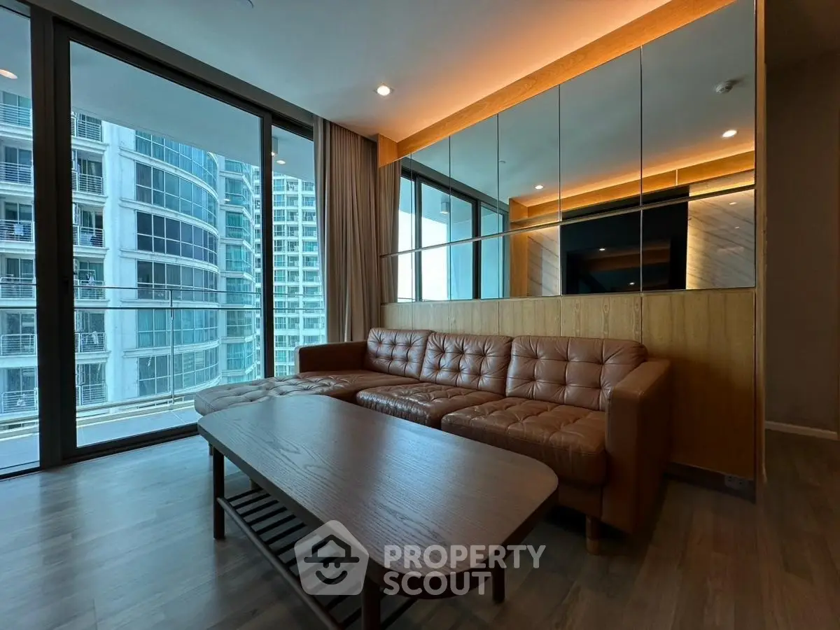 Modern living room with leather sofa and large windows offering city view
