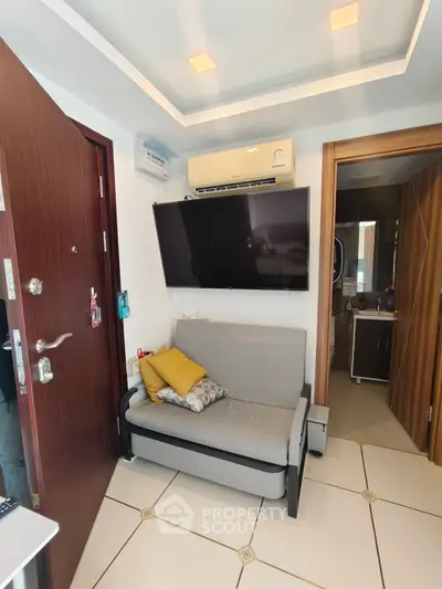 Compact living room with sofa, wall-mounted TV, and air conditioning unit