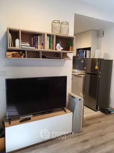 Modern living room with sleek TV setup and compact kitchen area, perfect for urban living.