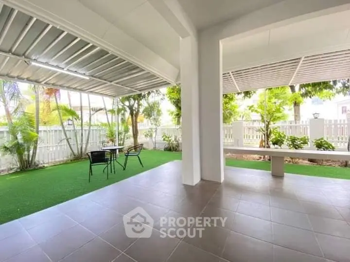 Spacious covered patio with lush garden view, perfect for outdoor relaxation and entertainment.