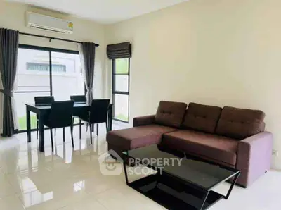 Modern living room with brown sofa and dining area, bright natural light