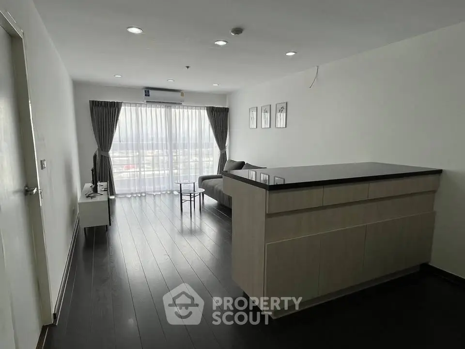 Spacious modern living room with sleek dark flooring and large windows offering natural light.