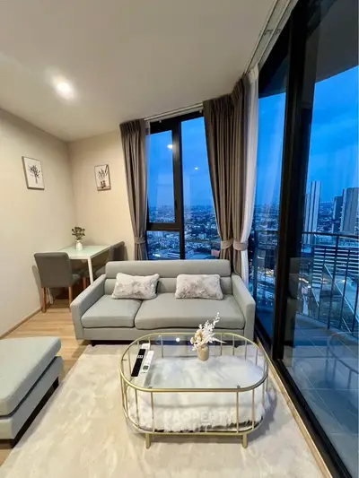 Modern living room with city view, stylish furniture, and floor-to-ceiling windows.