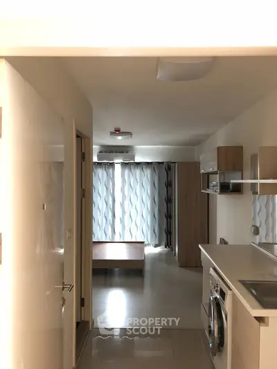 Modern apartment interior with open kitchen and washing machine, featuring sleek design and natural light.