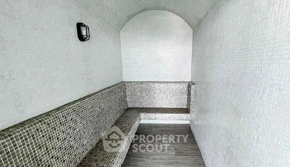 Luxurious steam room with elegant mosaic tiles and modern lighting, perfect for relaxation and wellness.