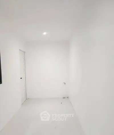 Minimalist white room with closed door and bright lighting, perfect for creative design opportunities.