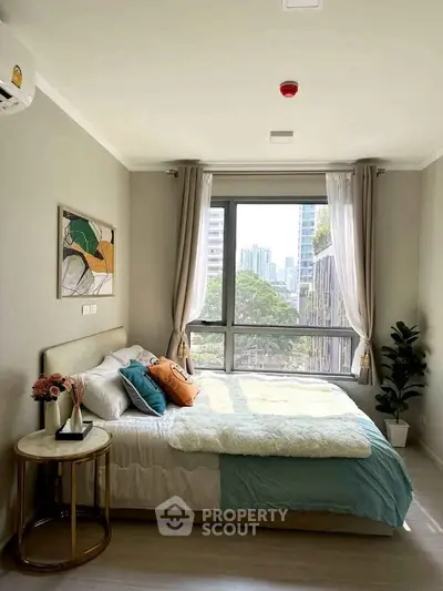 Bright and cozy bedroom with large window and modern decor in urban apartment.