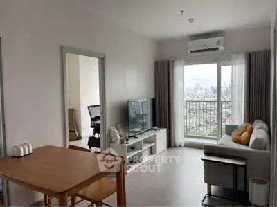 Modern living room with city view, featuring sleek furniture and large windows for natural light.