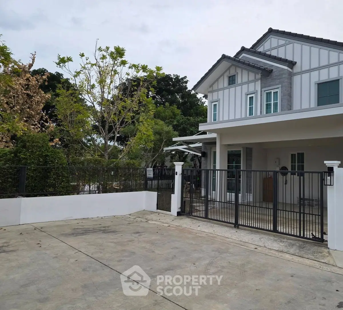 Modern two-story house with gated driveway and lush greenery