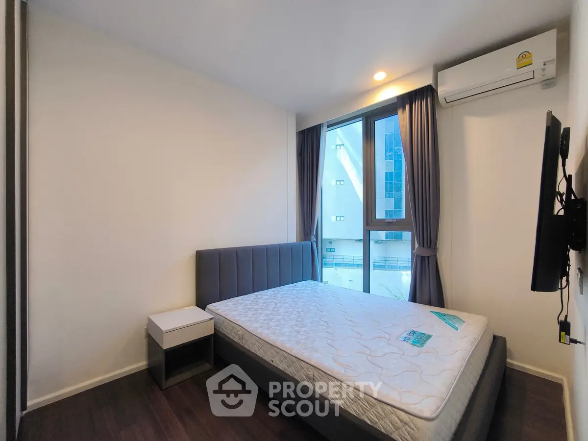 Modern bedroom with large window and air conditioning in a stylish apartment.