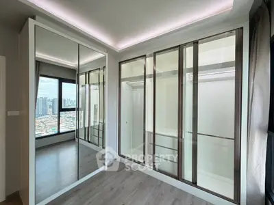 Spacious modern bedroom with large mirrored closet and city view, perfect for urban living.