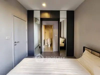 Modern bedroom with mirrored wardrobe and view into bathroom