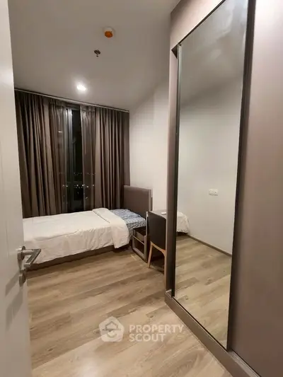 Modern bedroom with sleek design, wooden flooring, and large window with curtains.