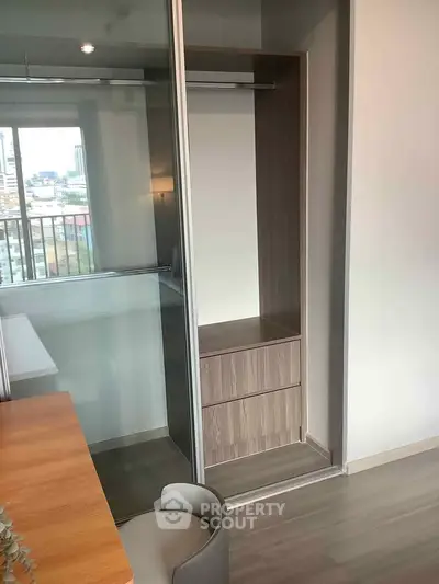 Modern apartment interior with built-in closet and city view from window.